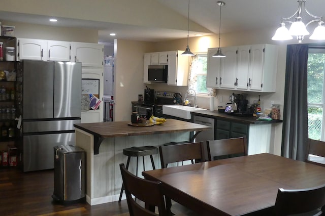 kitchen featuring appliances with stainless steel finishes, dark hardwood / wood-style flooring, white cabinetry, and pendant lighting