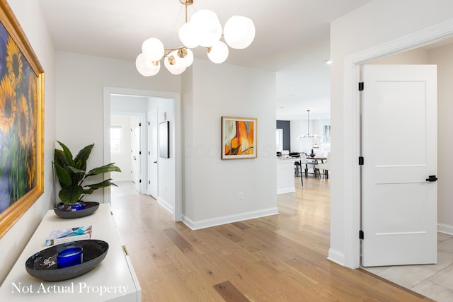 hall with light hardwood / wood-style floors and an inviting chandelier