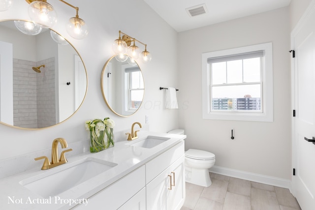 bathroom with tiled shower, vanity, and toilet