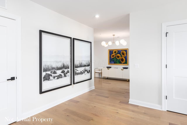 hall featuring light hardwood / wood-style flooring and an inviting chandelier