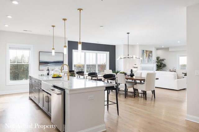 kitchen with hanging light fixtures, plenty of natural light, and a kitchen island with sink