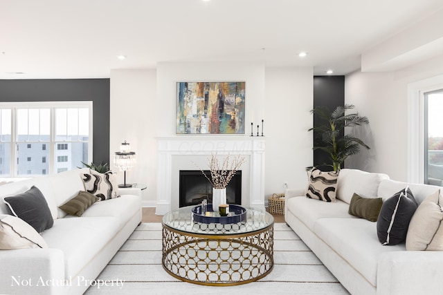 living room with a healthy amount of sunlight, a high end fireplace, and light hardwood / wood-style flooring