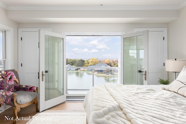 bedroom featuring a water view, light wood-type flooring, crown molding, and multiple windows