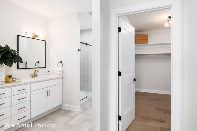 bathroom with a shower with shower door, wood-type flooring, and vanity