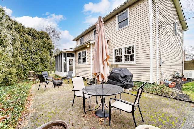 view of patio with grilling area, a sunroom, and an outdoor fire pit