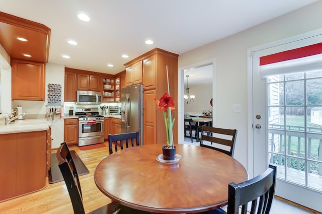 dining space featuring an inviting chandelier, sink, a wealth of natural light, and light wood-type flooring