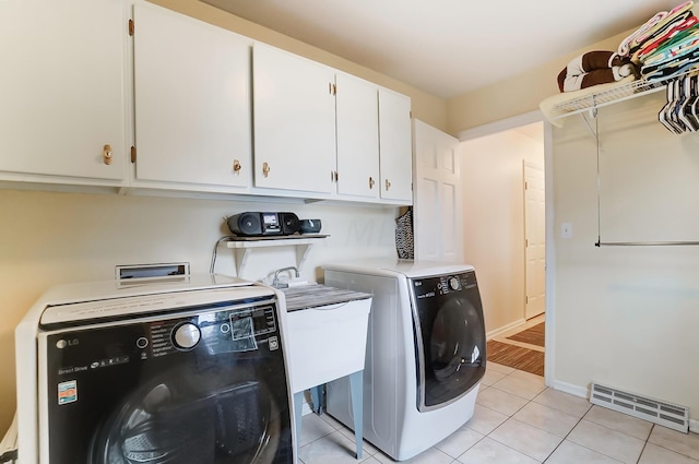 washroom with cabinets, light tile patterned floors, and washer and dryer