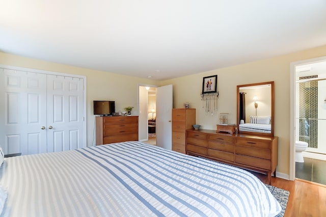 bedroom with ensuite bathroom, light hardwood / wood-style floors, and a closet