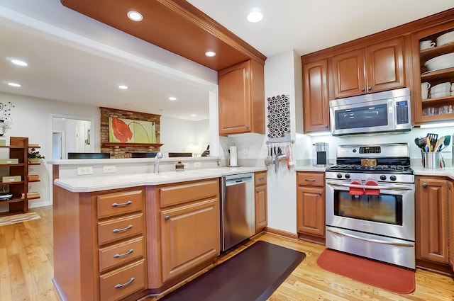 kitchen featuring light hardwood / wood-style floors, kitchen peninsula, and appliances with stainless steel finishes