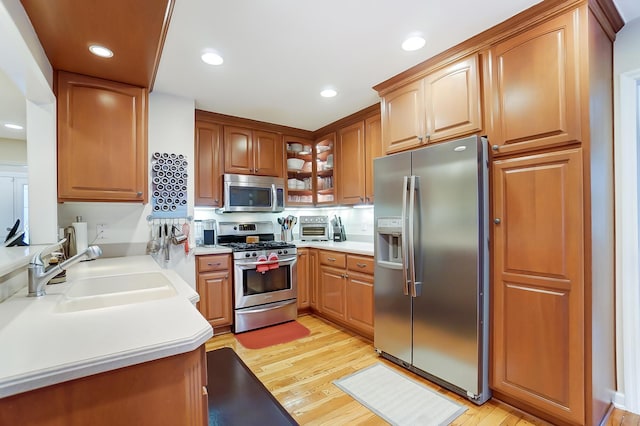 kitchen with stainless steel appliances, light hardwood / wood-style floors, and sink