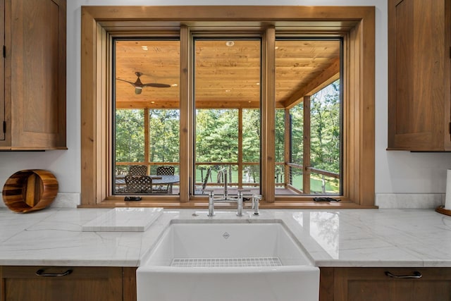 kitchen with light stone counters, wooden ceiling, sink, and a wealth of natural light