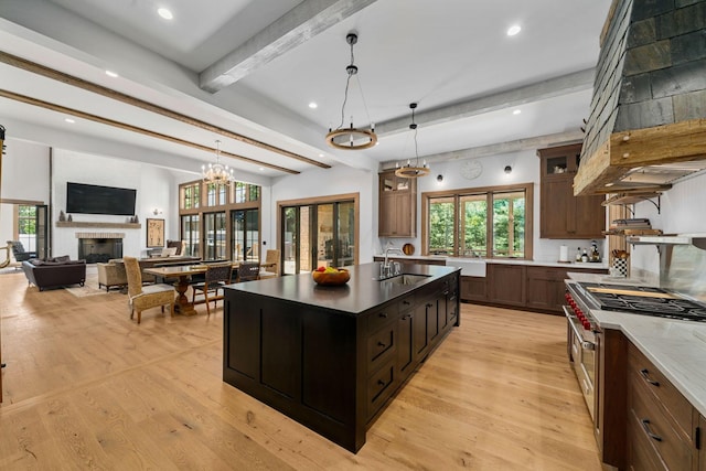 kitchen featuring beam ceiling, sink, pendant lighting, double oven range, and light hardwood / wood-style floors