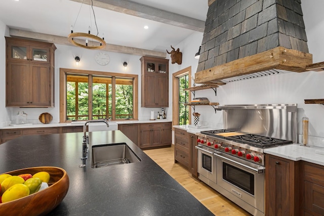 kitchen featuring custom exhaust hood, double oven range, sink, light wood-type flooring, and beam ceiling