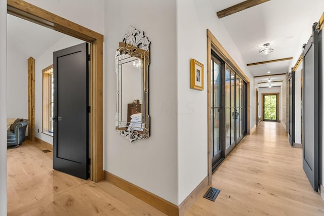 hall featuring lofted ceiling, a barn door, and light wood-type flooring