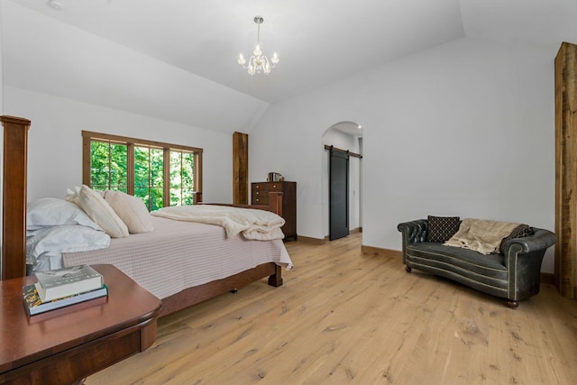 bedroom with a barn door, a notable chandelier, vaulted ceiling, and light wood-type flooring