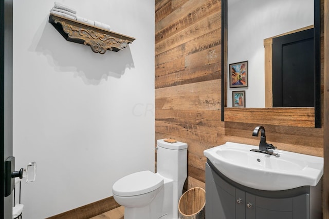 bathroom featuring hardwood / wood-style flooring, vanity, toilet, and wooden walls