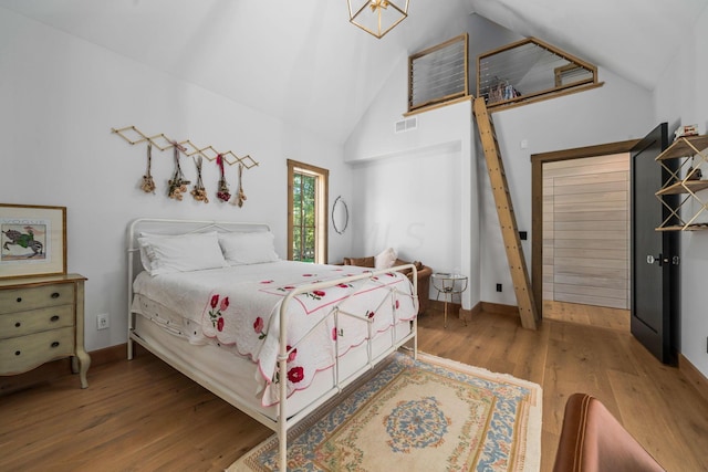 bedroom featuring wood-type flooring and high vaulted ceiling