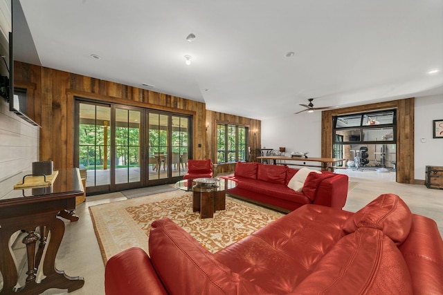 living room with ceiling fan, wood walls, and french doors