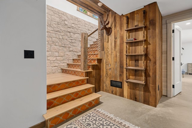 stairway featuring carpet and wood walls