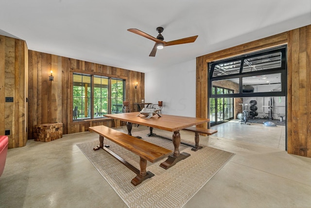 dining room with ceiling fan and wooden walls