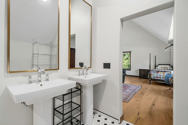 bathroom with hardwood / wood-style floors, double sink, and lofted ceiling