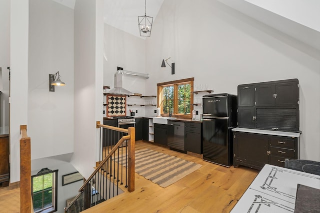 kitchen featuring sink, stainless steel appliances, high vaulted ceiling, light hardwood / wood-style floors, and decorative light fixtures