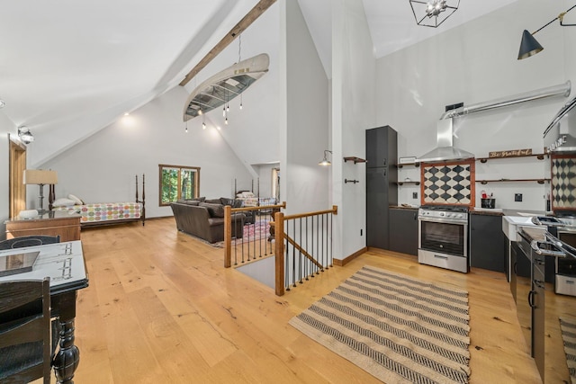 kitchen featuring light wood-type flooring, island exhaust hood, high vaulted ceiling, and stainless steel gas range