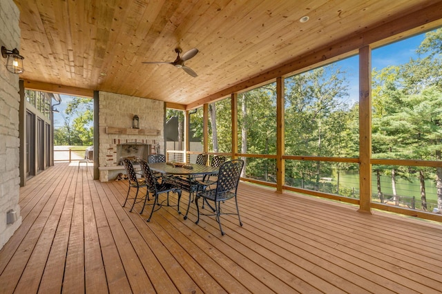 wooden terrace with an outdoor stone fireplace and ceiling fan