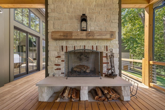 sunroom featuring beam ceiling, a wealth of natural light, and an outdoor stone fireplace