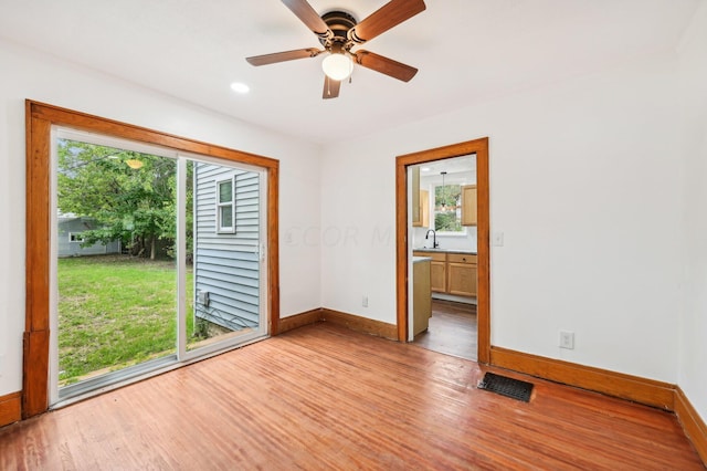 unfurnished room with sink, light wood-type flooring, plenty of natural light, and ceiling fan