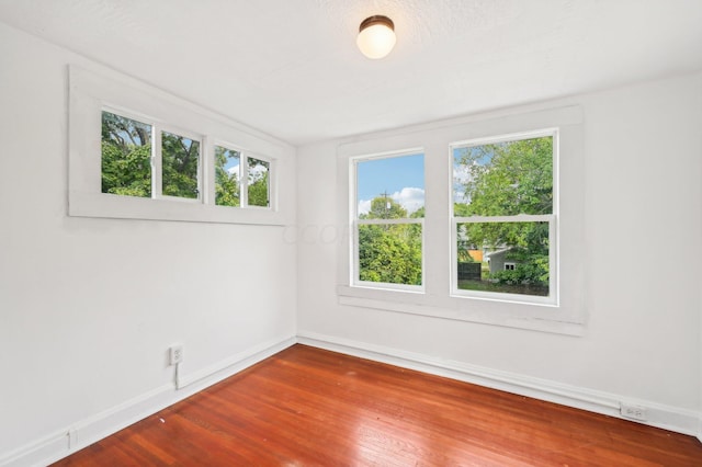 unfurnished room with a healthy amount of sunlight and hardwood / wood-style flooring