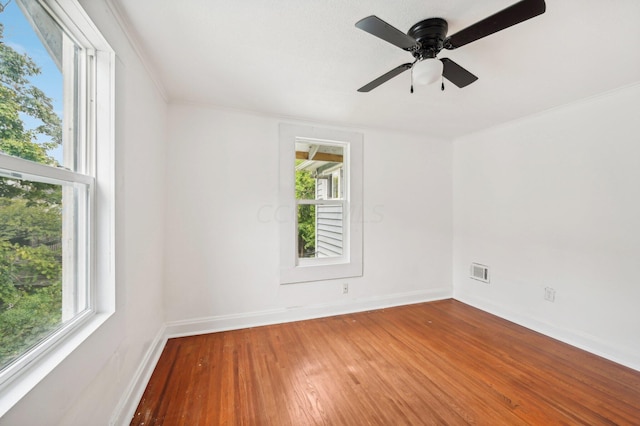 unfurnished room featuring ceiling fan, a healthy amount of sunlight, wood-type flooring, and ornamental molding