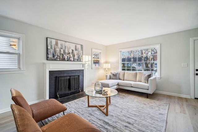 living room with a brick fireplace and light wood-type flooring