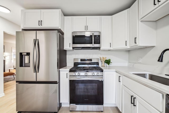 kitchen featuring white cabinets, sink, stainless steel appliances, and light hardwood / wood-style flooring