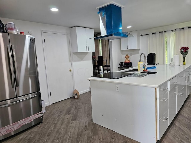 kitchen with dark wood-type flooring, white cabinets, sink, stainless steel fridge, and island range hood