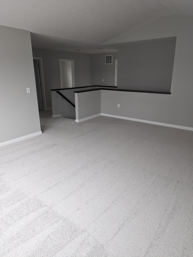 carpeted empty room with vaulted ceiling