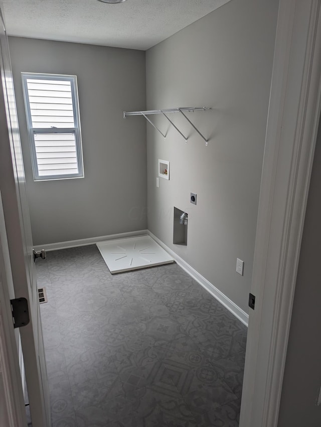 clothes washing area with hookup for an electric dryer, washer hookup, and a textured ceiling