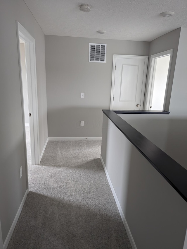 hallway with carpet flooring and a textured ceiling