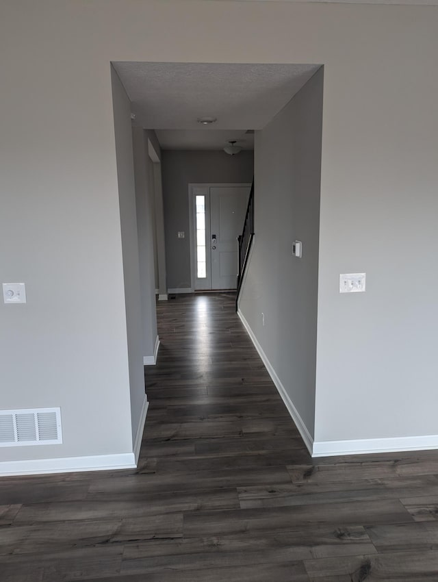 corridor featuring a textured ceiling and dark hardwood / wood-style floors