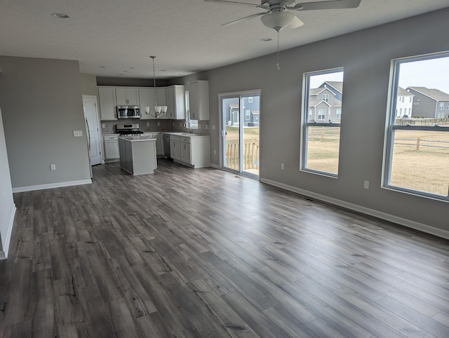 unfurnished living room featuring ceiling fan, dark wood-type flooring, and sink