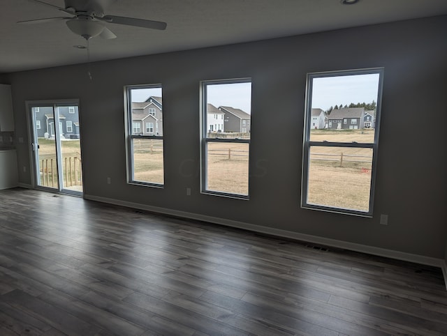 spare room featuring ceiling fan, plenty of natural light, and dark hardwood / wood-style floors