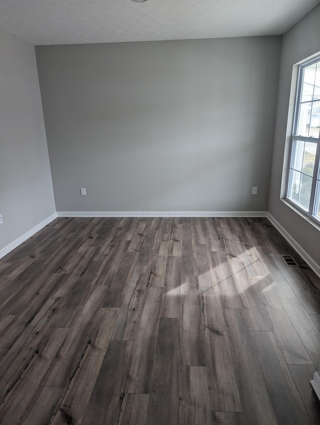 empty room with dark hardwood / wood-style floors and a textured ceiling