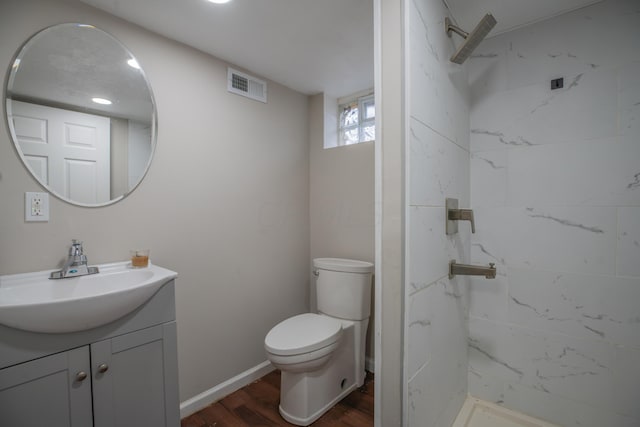 bathroom featuring a tile shower, toilet, vanity, and hardwood / wood-style flooring