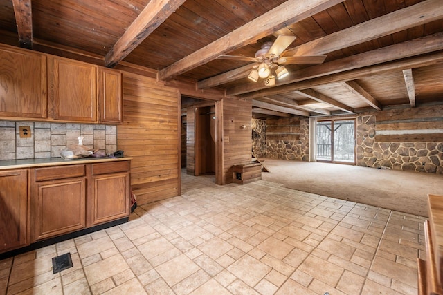 kitchen with ceiling fan, wood walls, wooden ceiling, and beam ceiling