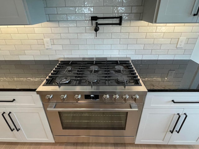 kitchen with white cabinets, light hardwood / wood-style floors, backsplash, and high end stainless steel range