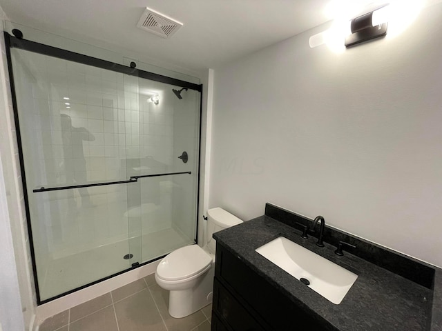 bathroom featuring tile patterned floors, vanity, toilet, and an enclosed shower