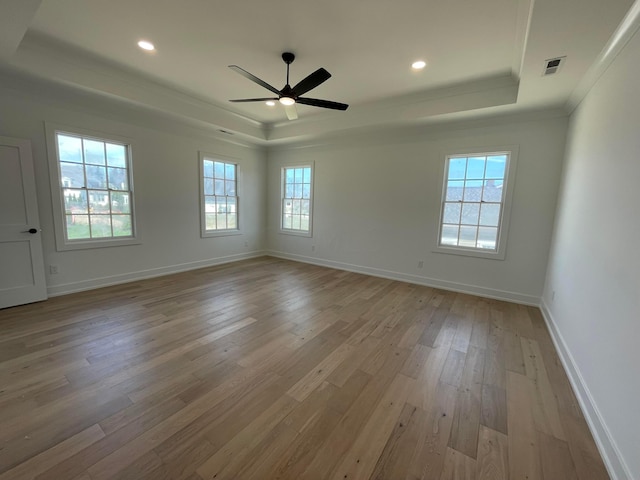 unfurnished room featuring a tray ceiling, ceiling fan, crown molding, and light hardwood / wood-style floors