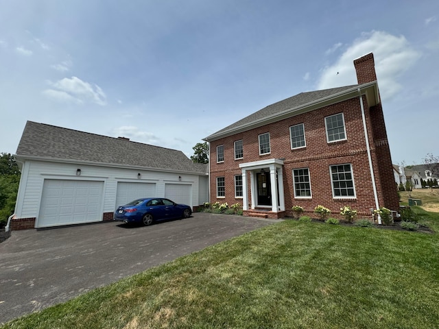 colonial home with a garage and a front lawn