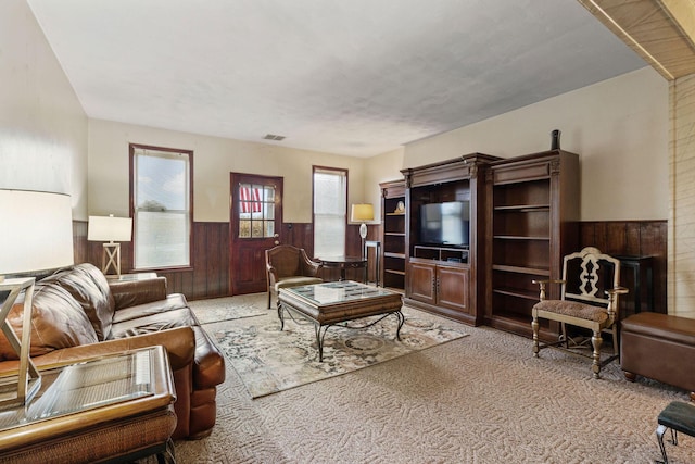 carpeted living room featuring wood walls