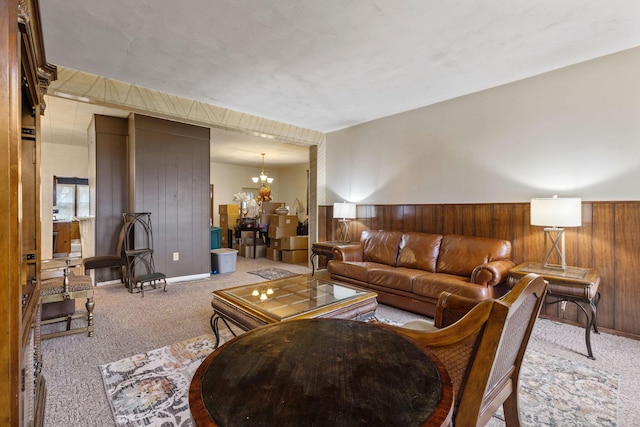 carpeted living room with wood walls and an inviting chandelier